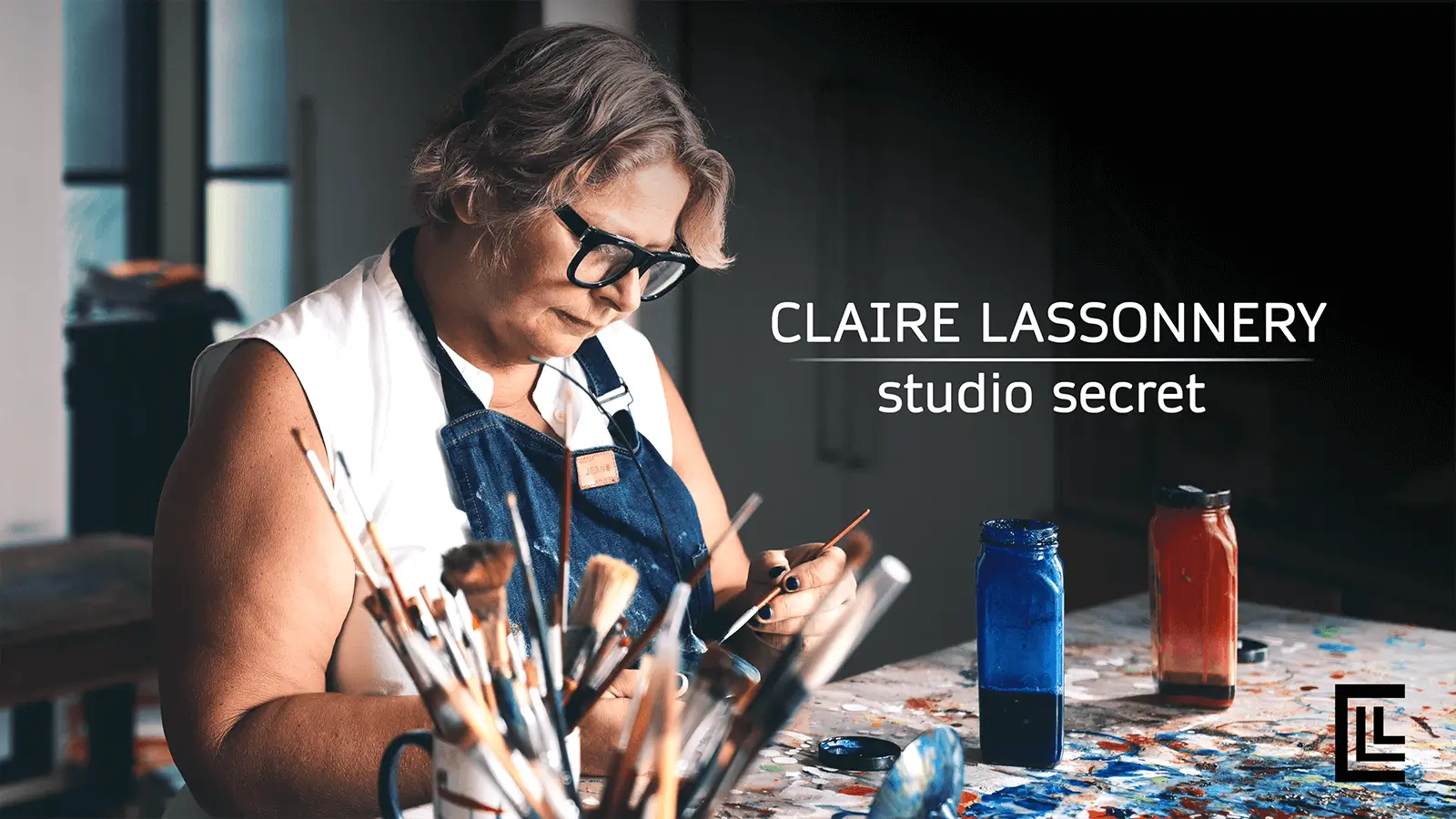 Claire Lassonnery, Studio Secret, studio process video, artist working at studio table, brushes and pigments in foreground, blue apron, Kuala Lumpur